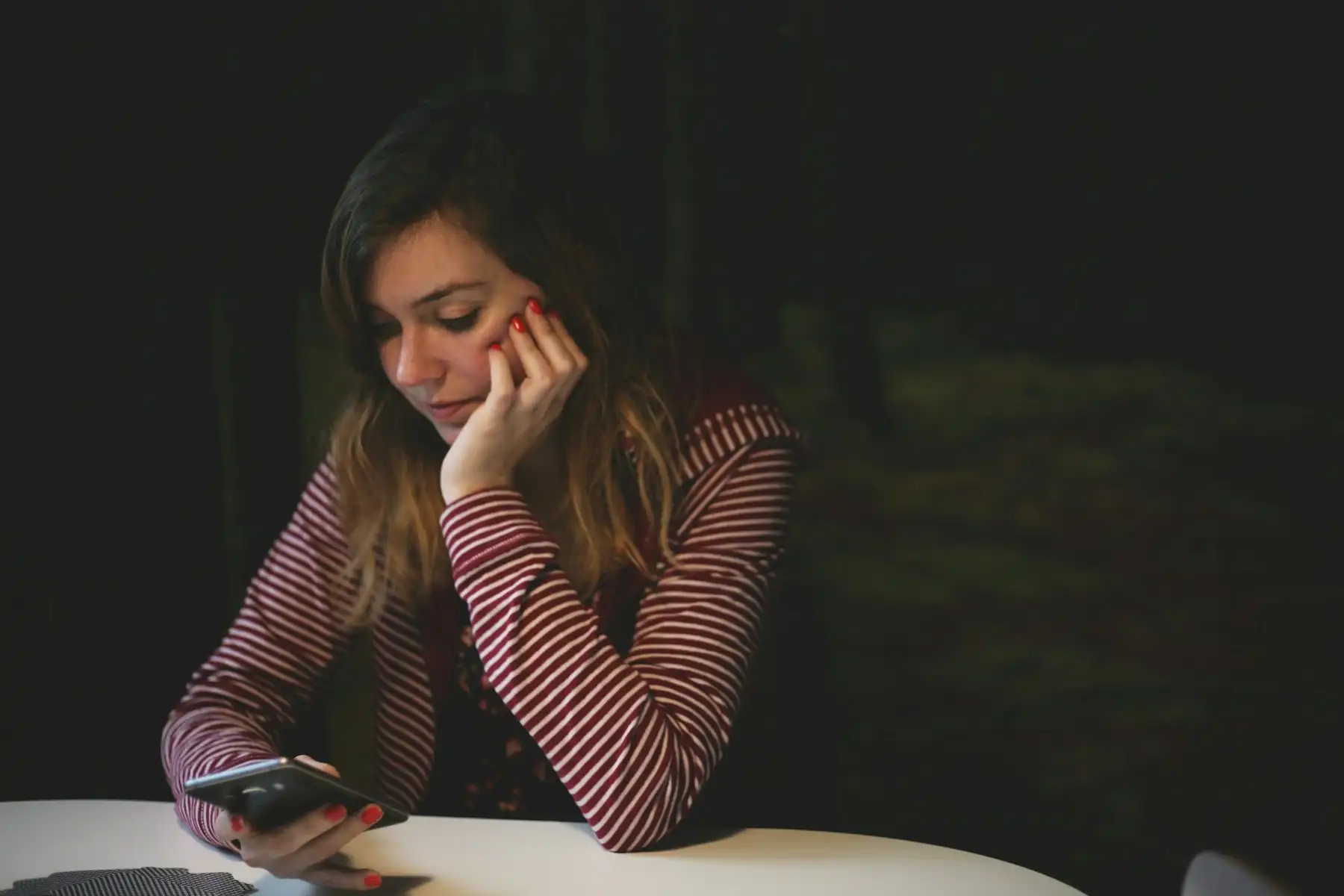 Mulher olhando o celular à noite