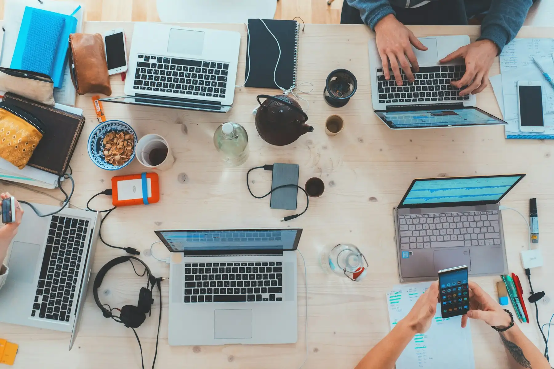 Mesa de trabalho vista de cima com notebooks e celulares